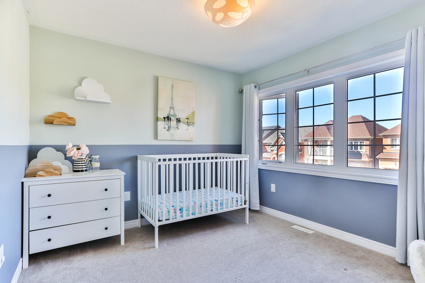 Soft blue nursery room with a white crib and calm bedding