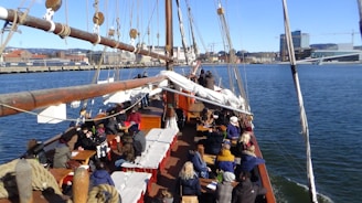 A diverse group of seafarers and consultants gathered around a ship's deck, sharing stories and plans under a bright sky.