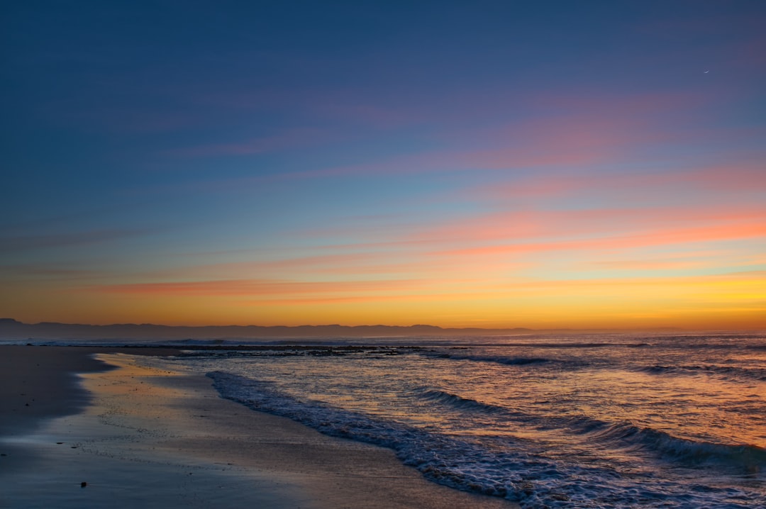 ocean waves crashing on shore during sunset