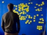 man in gray long sleeve shirt standing in front of blue and yellow puzzle mat