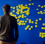 man in gray long sleeve shirt standing in front of blue and yellow puzzle mat