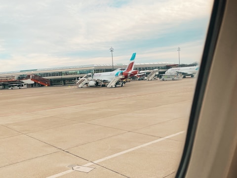 Modern airport terminal with airplanes parked and passengers walking.