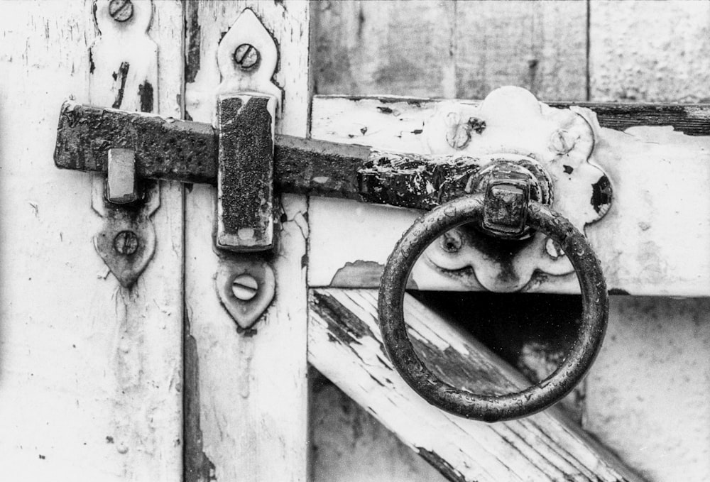 Foto en escala de grises de una cadena de metal en una puerta de madera