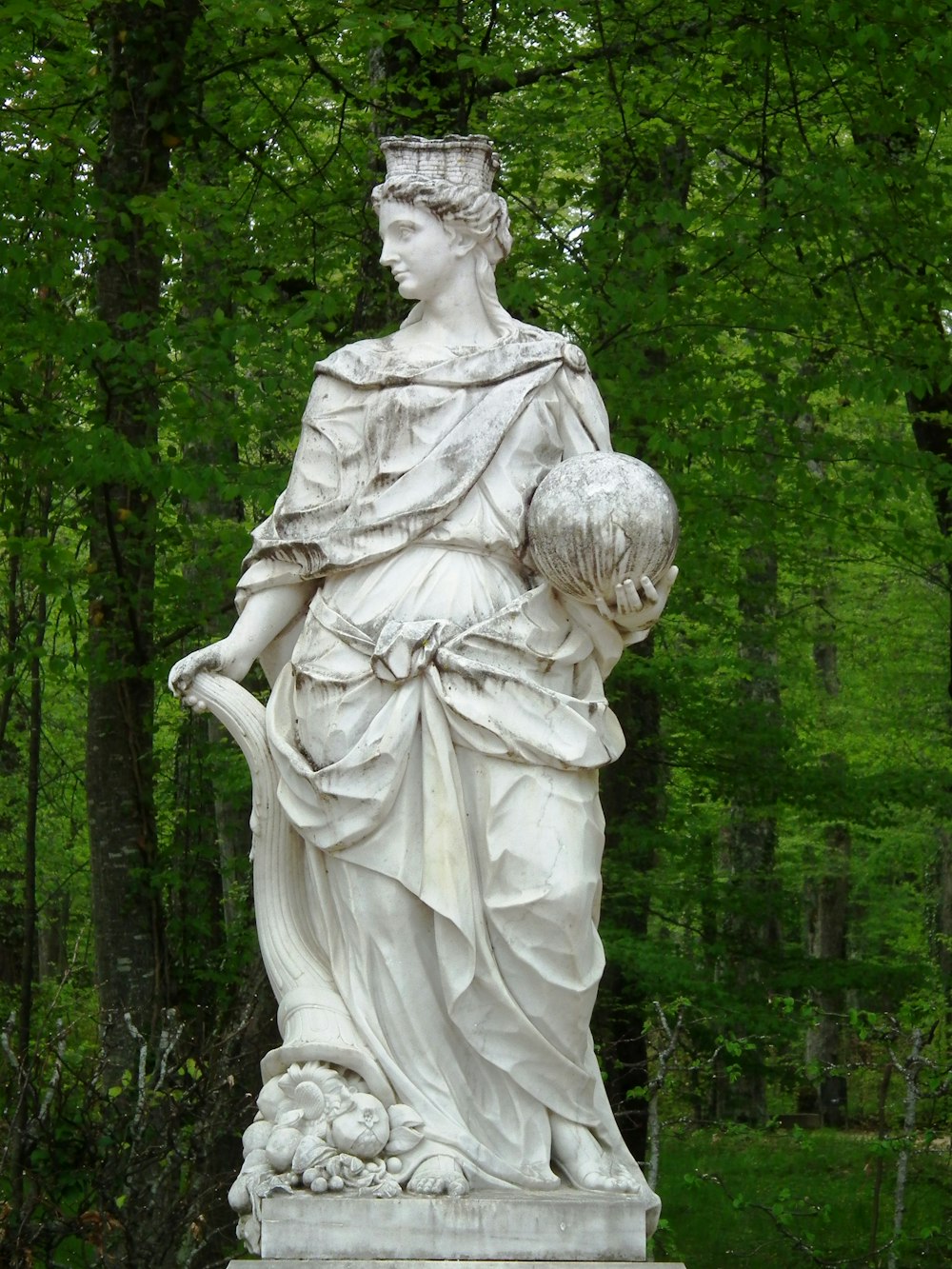 estátua do anjo perto de árvores verdes durante o dia