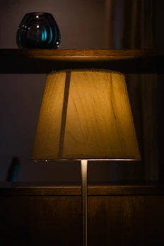 Close-up of a sleek ceramic lamp casting a warm glow on a modern shelf.
