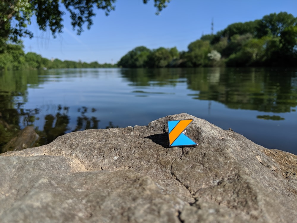 yellow and black triangular on gray rock near body of water during daytime