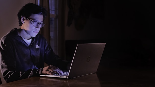 A focused editor reviewing news articles on a laptop in a bright office.