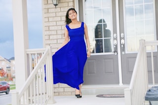 woman in blue sleeveless dress standing near white wooden door