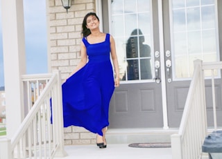 woman in blue sleeveless dress standing near white wooden door