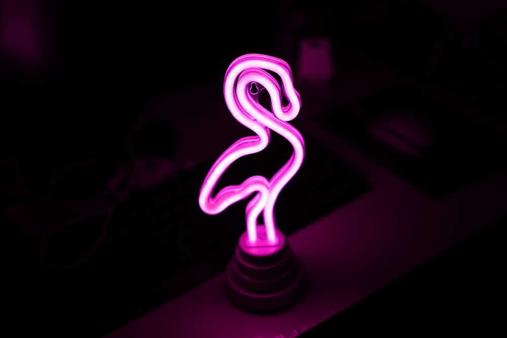 a pink neon sign sitting on top of a desk
