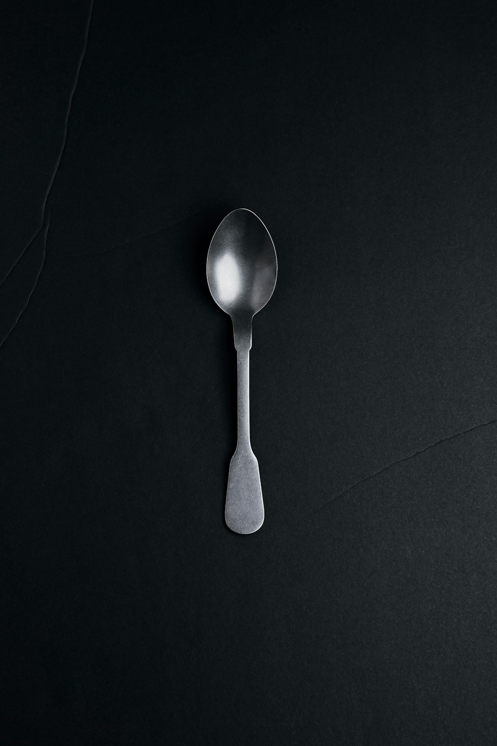 silver spoon on black textile