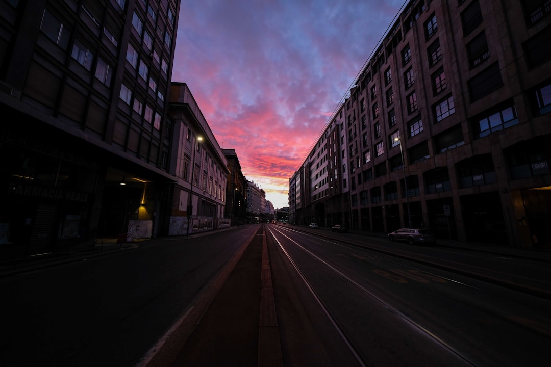 black asphalt road between buildings under cloudy sky during daytime