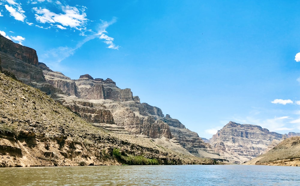 rocky mountain beside body of water under blue sky during daytime