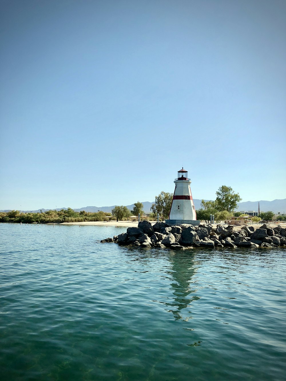 white and red lighthouse near body of water during daytime