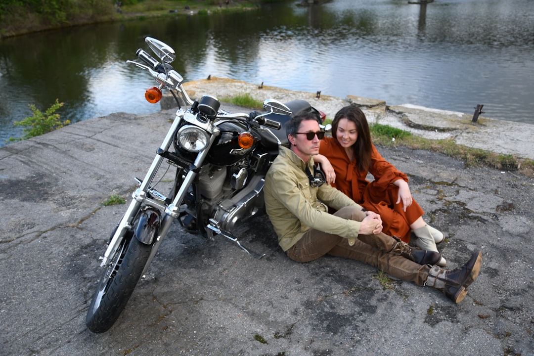 man and woman sitting on black motorcycle smiling