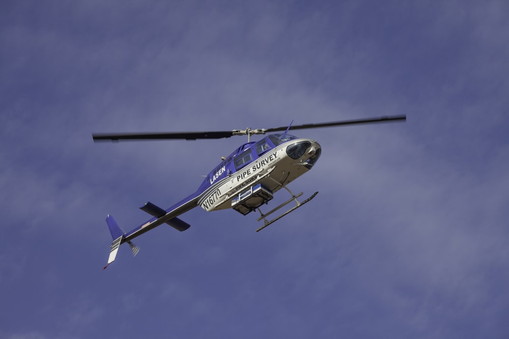 blue and white helicopter flying in the sky during daytime