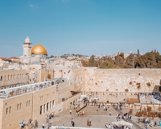 people walking on white sand near brown concrete building during daytime in Western Wall Israel