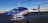 A blue and white helicopter is parked on an asphalt runway. The helicopter has 'PIPE SURVEY' written on its side, with additional text that includes 'LASEN' and 'N284CA'. The background features a clear blue sky and snow-covered mountains in the distance.