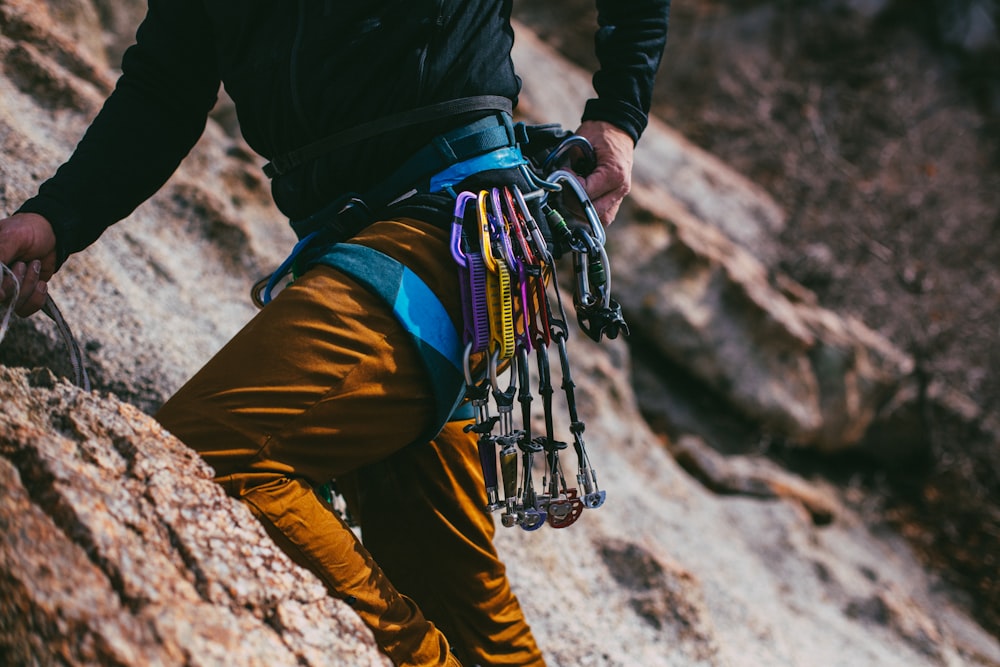 person in black jacket and brown pants with hiking backpack climbing mountain during daytime