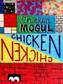 A colorful mural featuring the Naughty Chicken LLC logo painted on a rustic wooden wall.