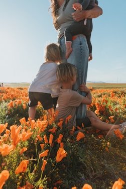 A group of volunteers warmly embracing children in a sunlit community garden.