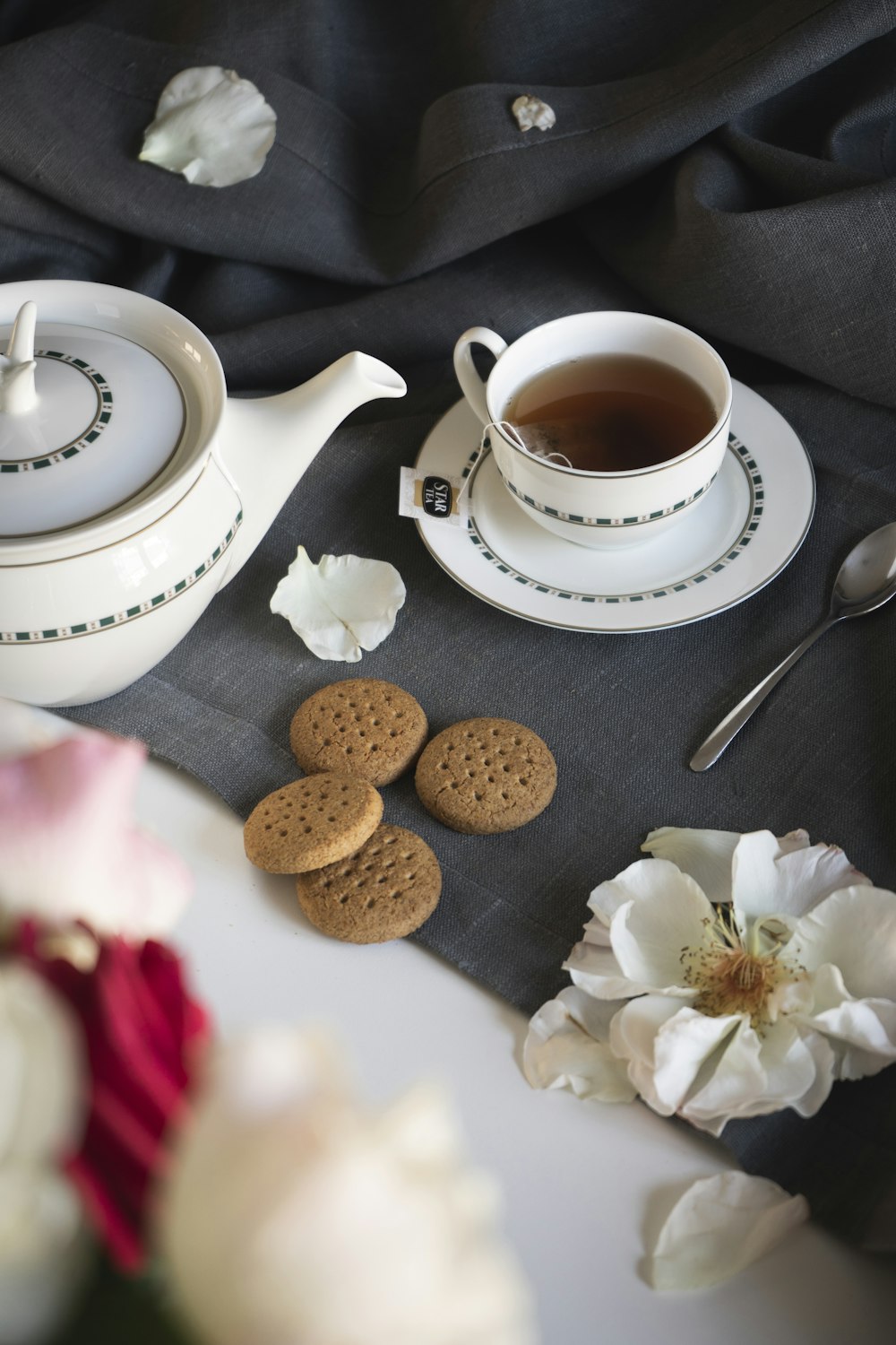 white ceramic teacup on saucer beside stainless steel spoon