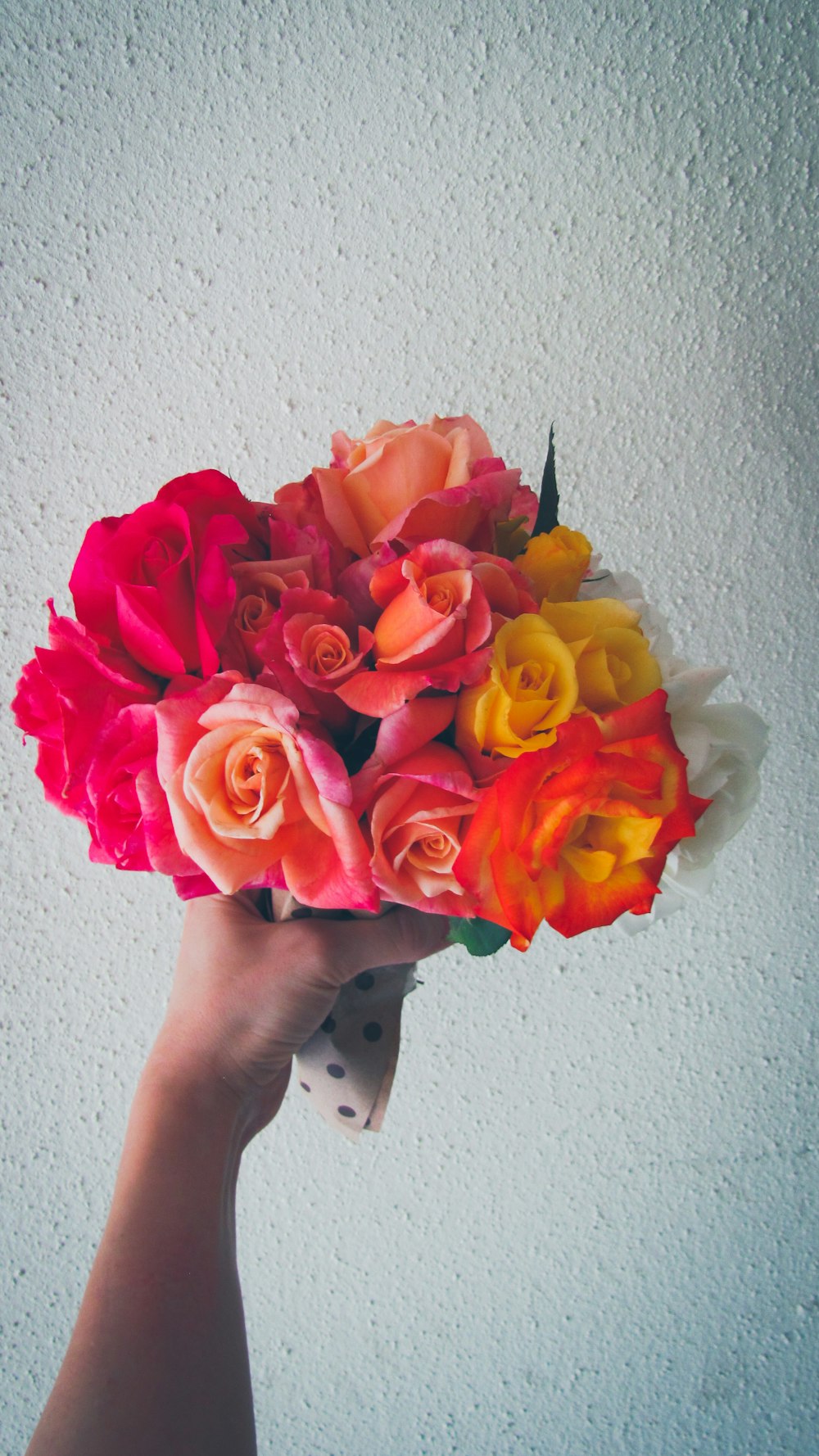 person holding red and yellow rose bouquet