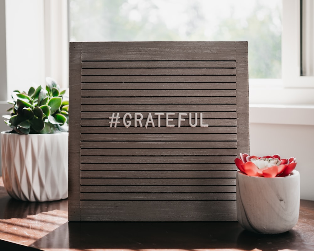 a wooden sign that says grateful next to a potted plant