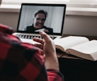person in red and black plaid long sleeve shirt using black laptop computer