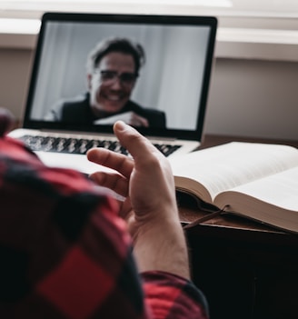 person in red and black plaid long sleeve shirt using black laptop computer