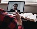person in red and black plaid long sleeve shirt using black laptop computer