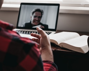 person in red shirt on a video call using laptop computer
