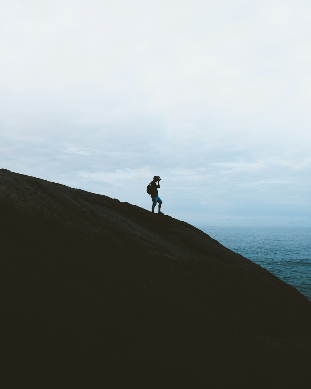 silhouette of person standing on top of mountain during daytime