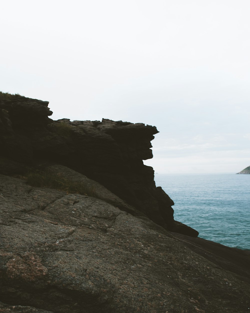 black rock formation near body of water during daytime