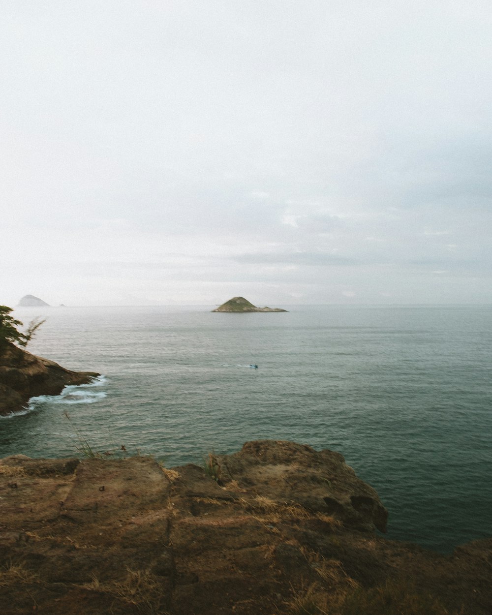 brown rock formation on sea under white sky during daytime