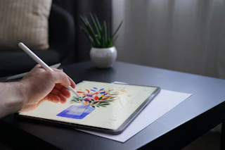 person holding white pen writing on white book