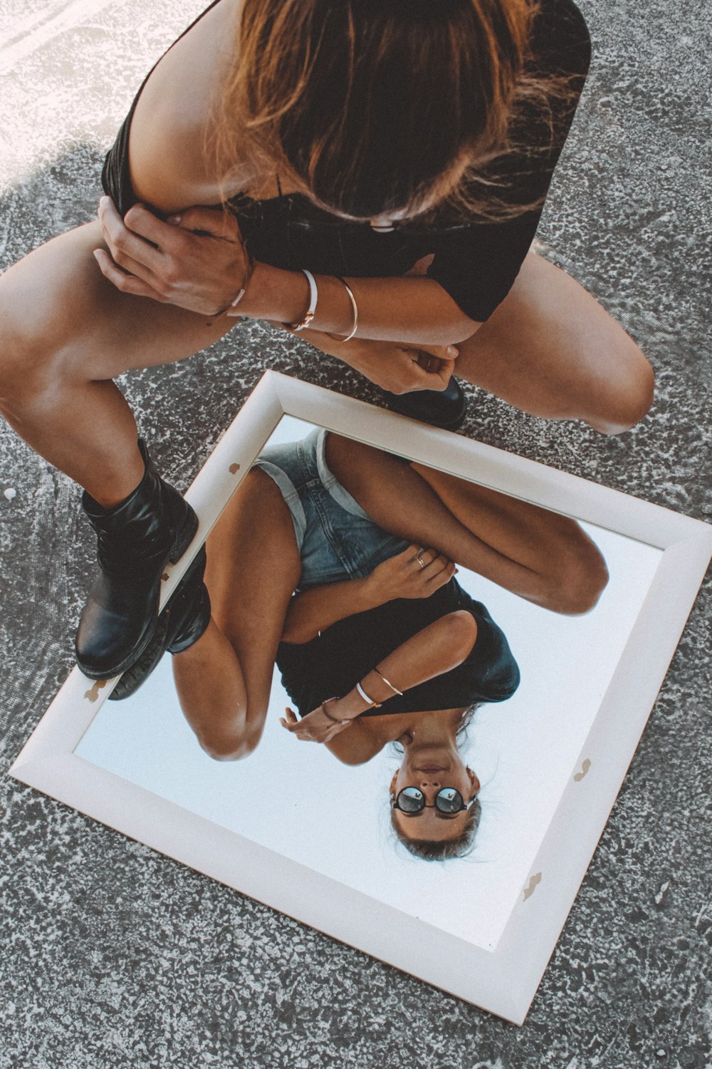 woman in black brassiere and blue denim shorts sitting on white wooden table