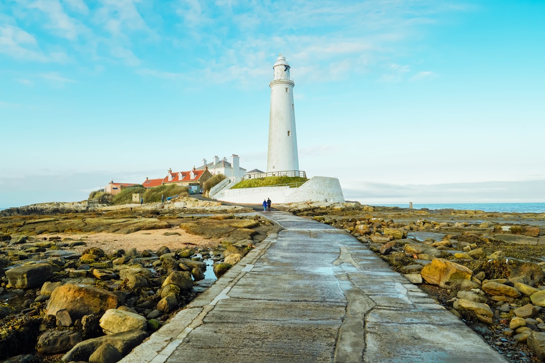 white lighthouse near brown and white concrete house under blue sky during daytime