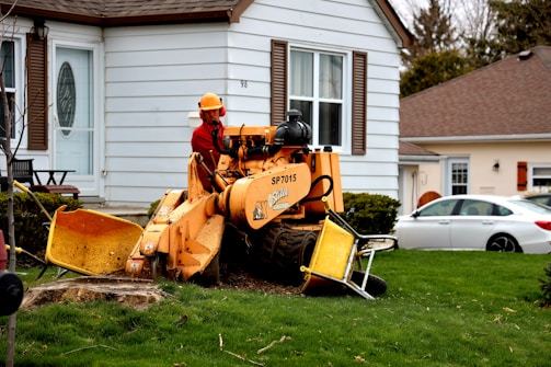 man in orange jacket sitting on yellow and black tractor