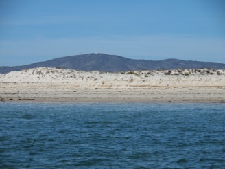 blue sea near mountain under blue sky during daytime