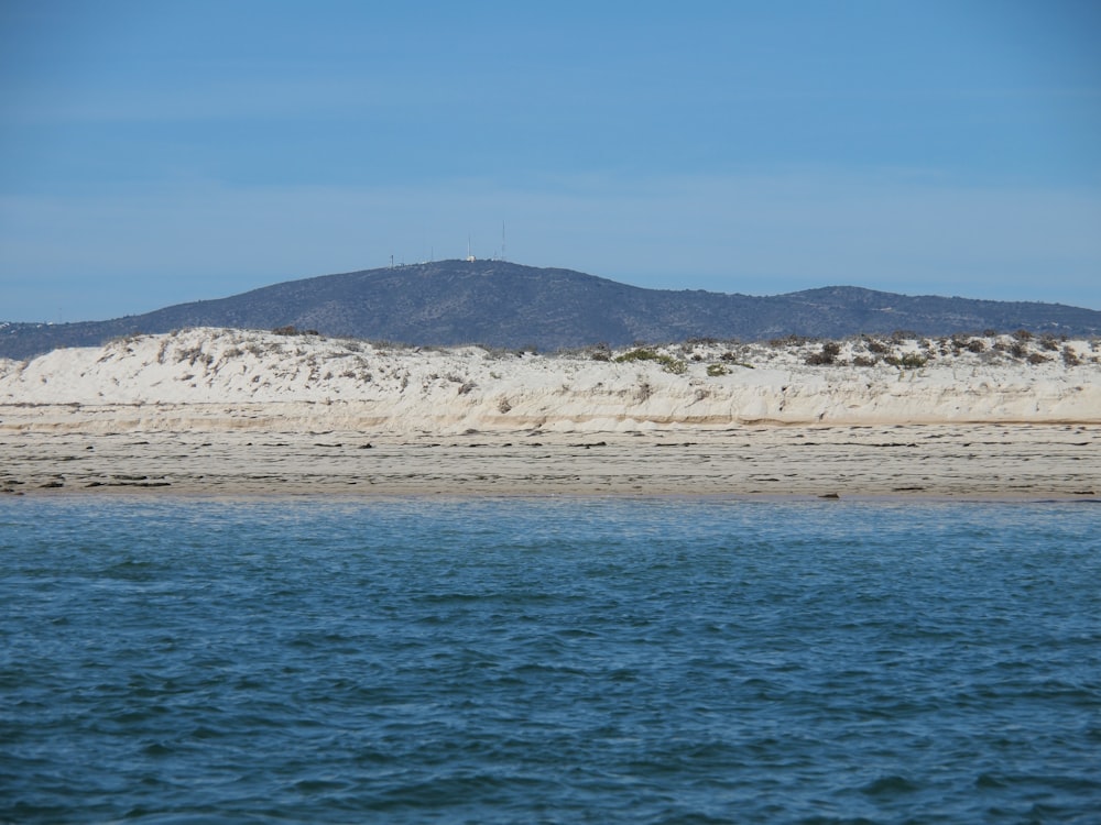 blue sea near mountain under blue sky during daytime