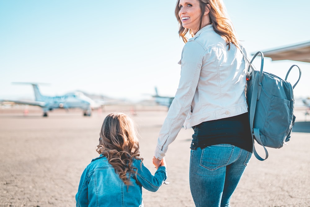woman in white long sleeve shirt and blue denim jeans holding girl in blue denim jacket