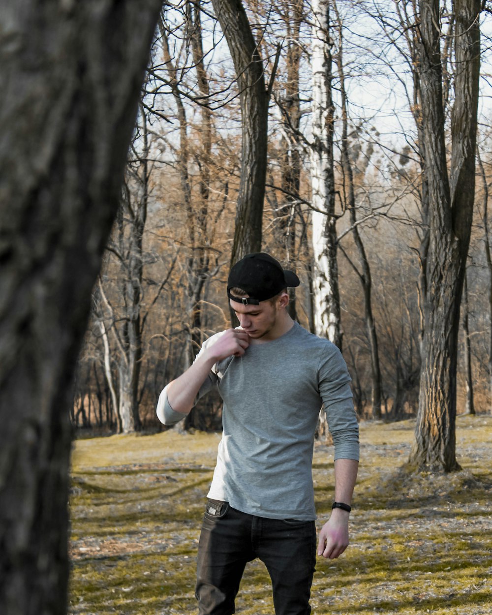 man in gray long sleeve shirt and black pants standing in forest during daytime