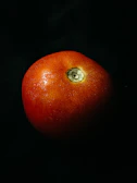 Photographer capturing the perfect shot of a ripe tomato with a crimson backdrop.