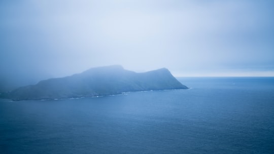 green mountain beside body of water during daytime in Runde Norway