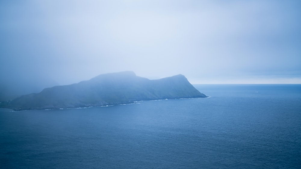 green mountain beside body of water during daytime