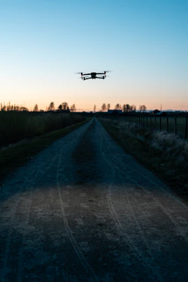 white drone flying over the green grass field during daytime
