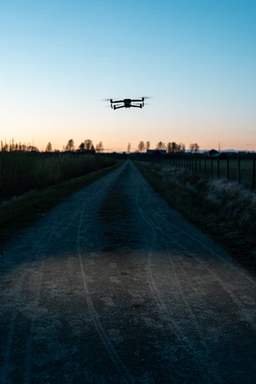 white drone flying over the green grass field during daytime