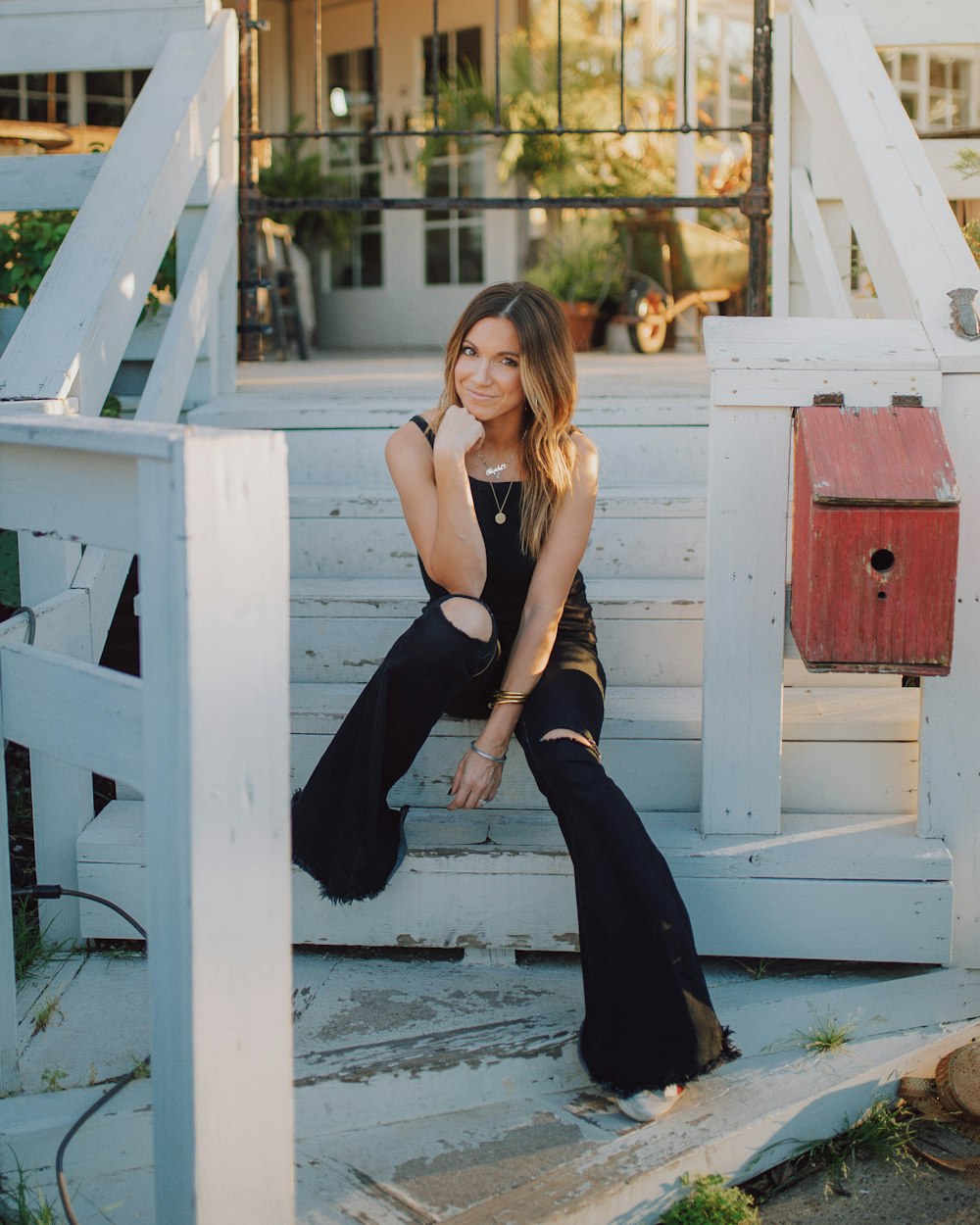 woman in black tank top and black pants sitting on white wooden bench during daytime