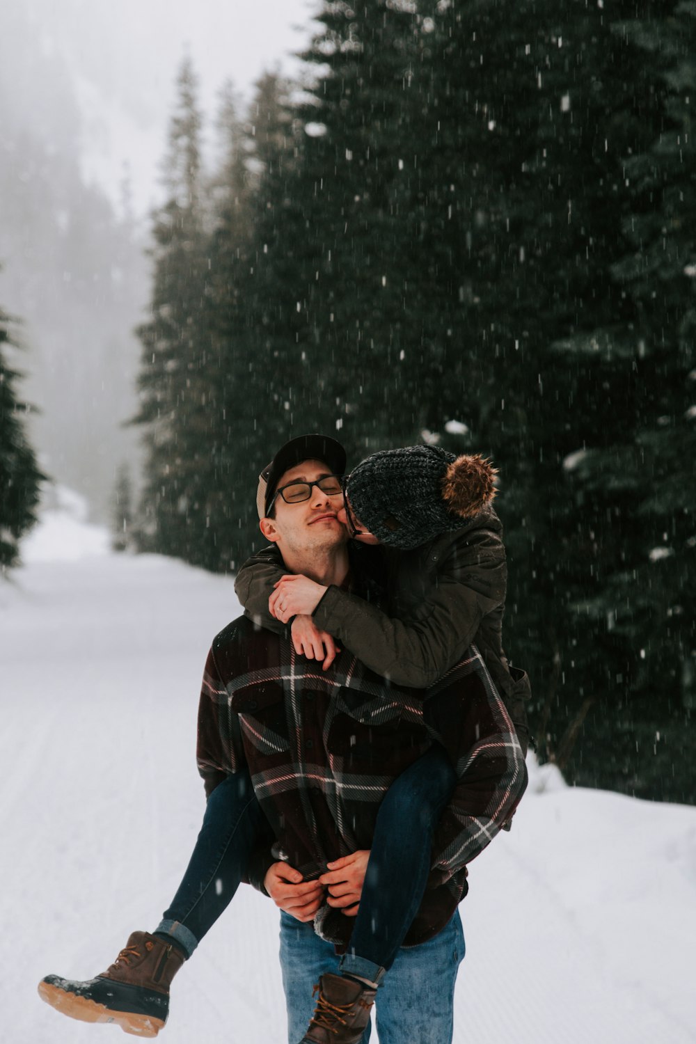 man in black jacket and blue denim jeans sitting on snow covered ground during daytime